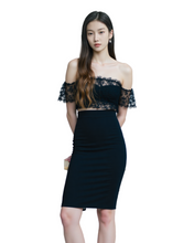 Woman wearing a black off-shoulder dress with lace details on a white background