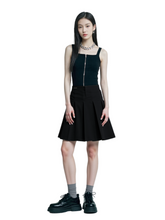Woman wearing a black sleeveless top and black skirt with platform shoes on a white background