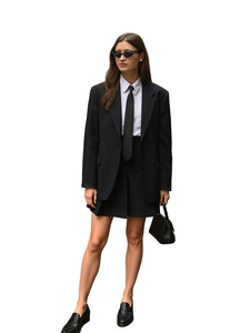 Woman in a black suit standing on a city street.