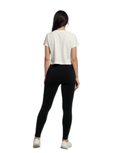 Person wearing a white t-shirt and black leggings on a plain background