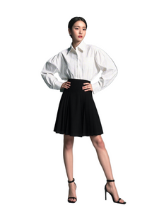Woman wearing a white shirt and black skirt on a gray background