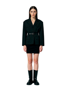 Woman wearing a black blazer and skirt set with black boots on a white background