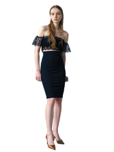 Woman wearing a black off-shoulder top and pencil skirt on a white background
