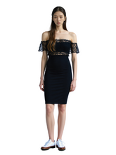 Woman wearing a black off-shoulder dress with lace details on a white background
