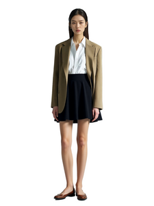 Woman wearing a brown blazer, white shirt, and black skirt on a white background