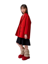 Child wearing a red coat, black skirt, and red shoes on a white background